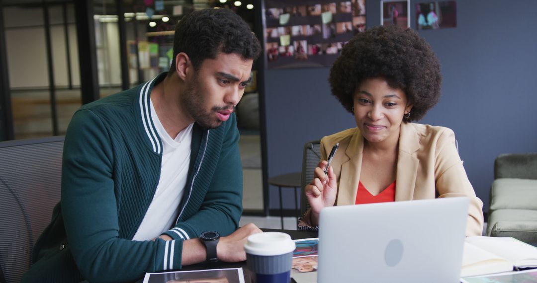 Colleagues Collaborating at Office Desk with Laptop and Papers