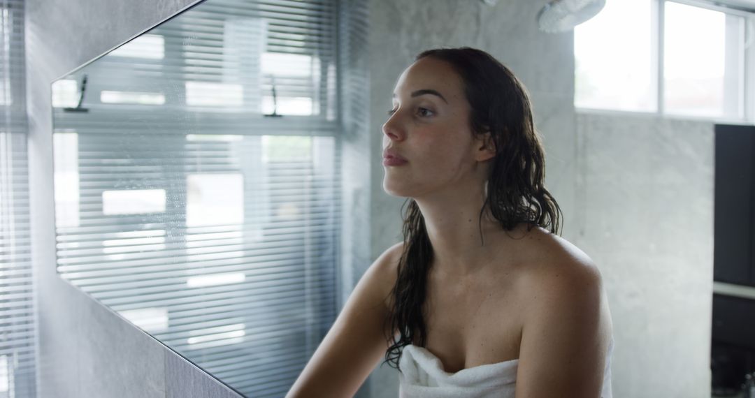 Woman Wrapped in Towel Looking at Herself in Bathroom Mirror - Free Images, Stock Photos and Pictures on Pikwizard.com