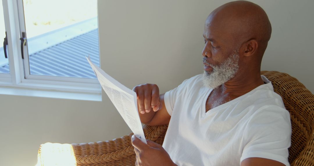 Side view of black mature man reading newspaper at home - Free Images, Stock Photos and Pictures on Pikwizard.com