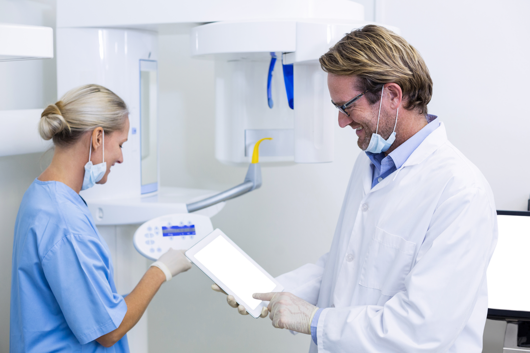 Dentist collaborating with assistant using transparent tablet in modern dental clinic - Download Free Stock Images Pikwizard.com