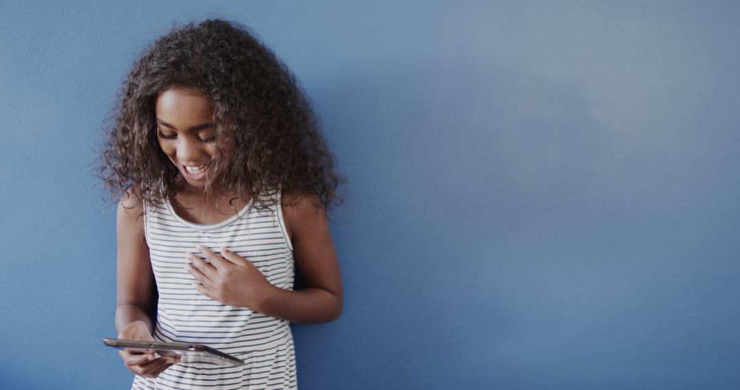 Smiling Biracial Girl Using Tablet Against Blue Background - Free Images, Stock Photos and Pictures on Pikwizard.com