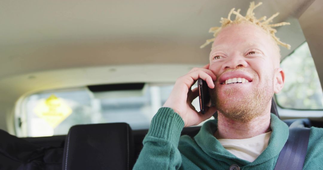 Smiling passenger talking on phone in rear car seat wearing green sweater and seatbelt