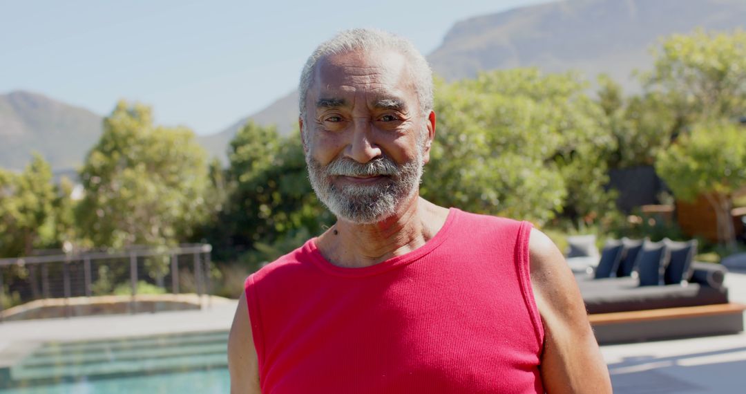 Smiling Senior Man Relaxing Outdoors Near Pool and Mountains - Free Images, Stock Photos and Pictures on Pikwizard.com