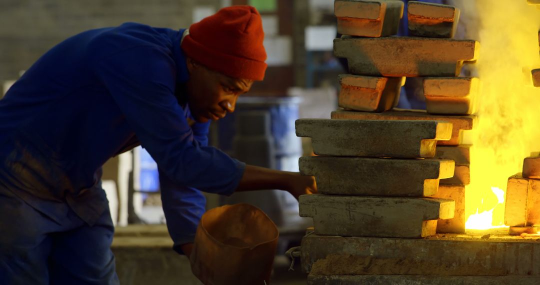 Worker in foundry pouring molten metal in molds with intense focus - Free Images, Stock Photos and Pictures on Pikwizard.com