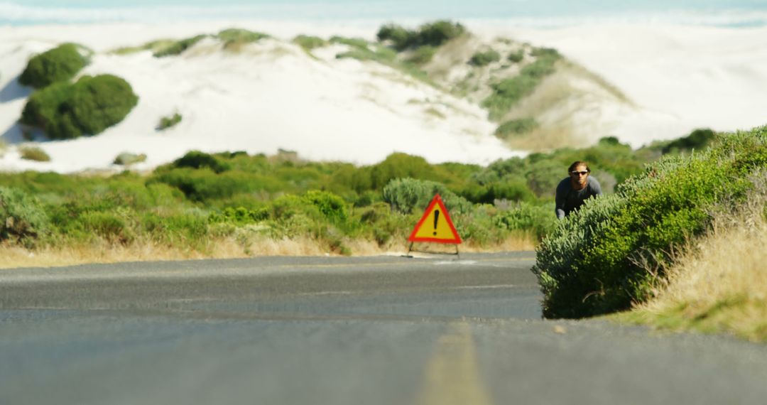 Cyclist Approaching Road Hazard Sign in Desert Landscape - Free Images, Stock Photos and Pictures on Pikwizard.com