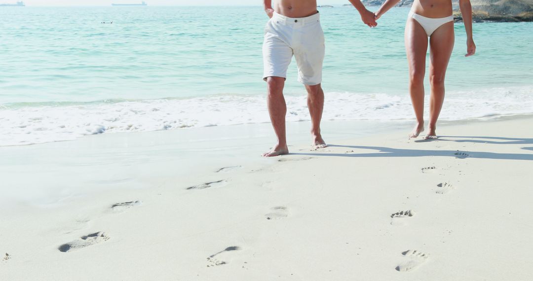 A Caucasian couple enjoys a romantic walk along a sandy beach, with copy space - Free Images, Stock Photos and Pictures on Pikwizard.com