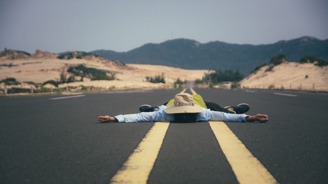 Person Lying on Desert Highway Photographed from Distance - Free Images, Stock Photos and Pictures on Pikwizard.com