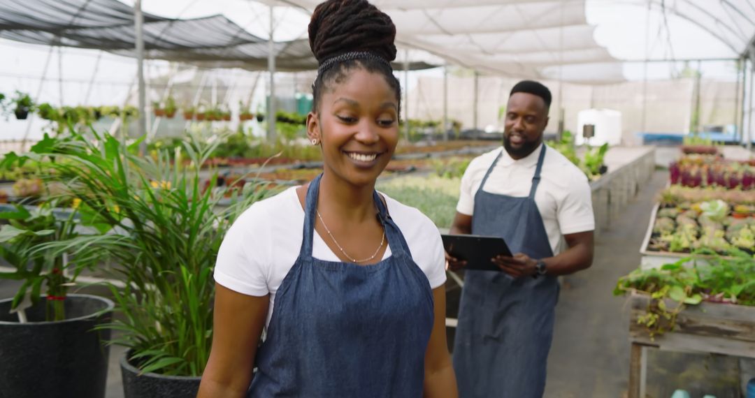 Smiling Coworkers Working Together in Lush Greenhouse