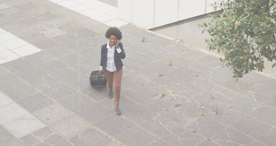 Confident Businesswoman Talking on Smartphone While Pulling Briefcase