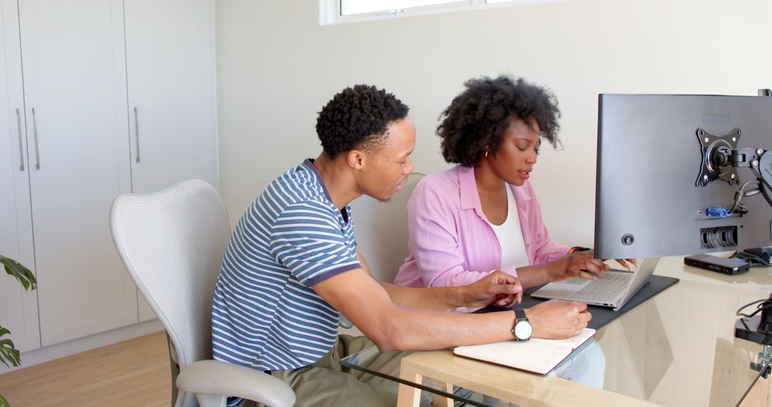Joyful Couple Collaborating at Home Desk on Laptop
