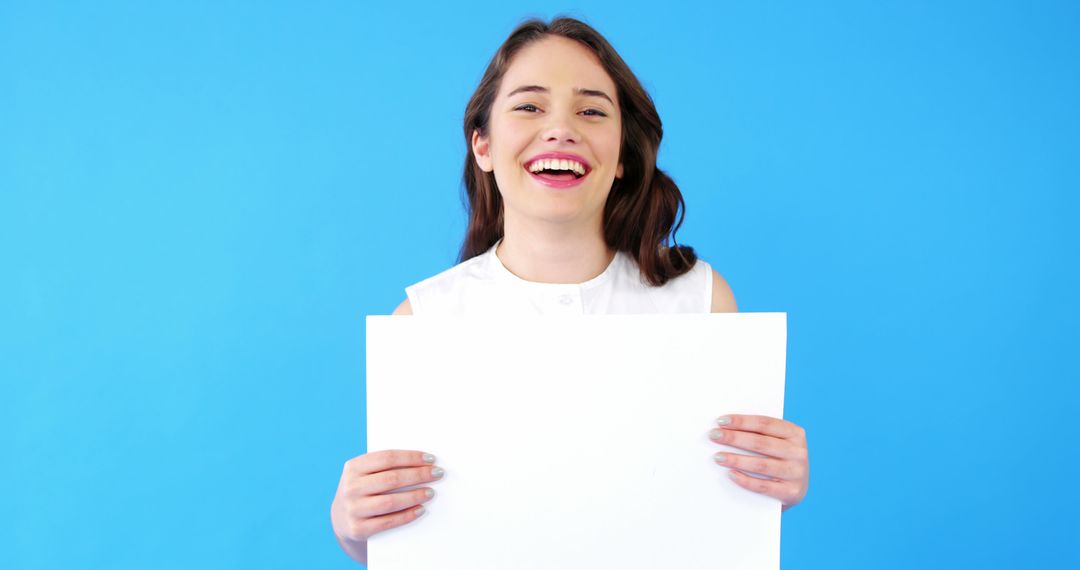 Happy Woman Holding Blank White Sign against Blue Background - Free Images, Stock Photos and Pictures on Pikwizard.com