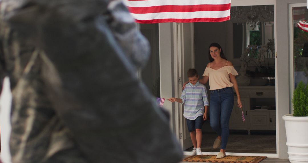 Caucasian male soldier greeting son and wife in garden with american flag hanging outside house - Free Images, Stock Photos and Pictures on Pikwizard.com