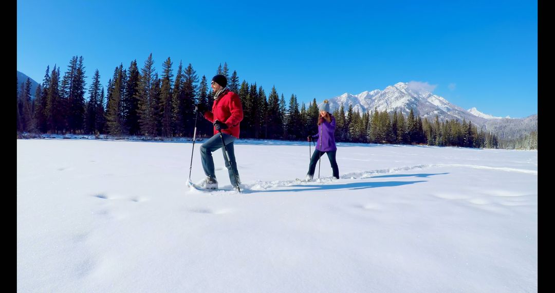 Couple Snowshoeing in a Scenic Winter Landscape with Mountains - Free Images, Stock Photos and Pictures on Pikwizard.com