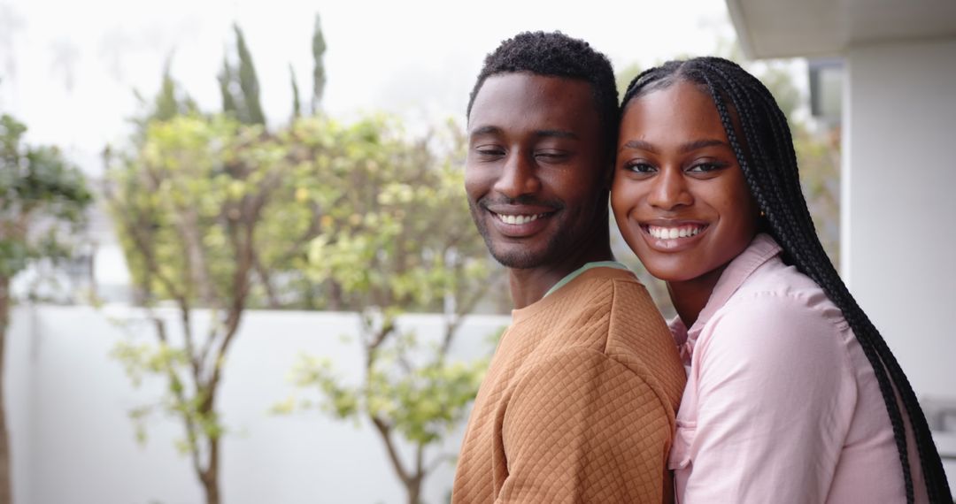 Couple Embracing on Balcony Overlooking Leafy Garden