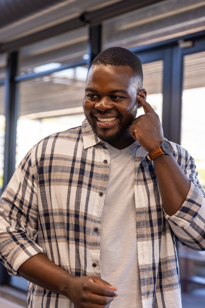 Smiling Professional Touching Ear in Modern Office