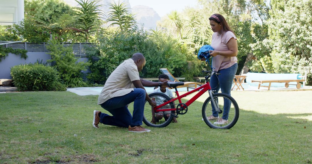 Father Teaching Child to Ride Bicycle on Sunny Day in Backyard