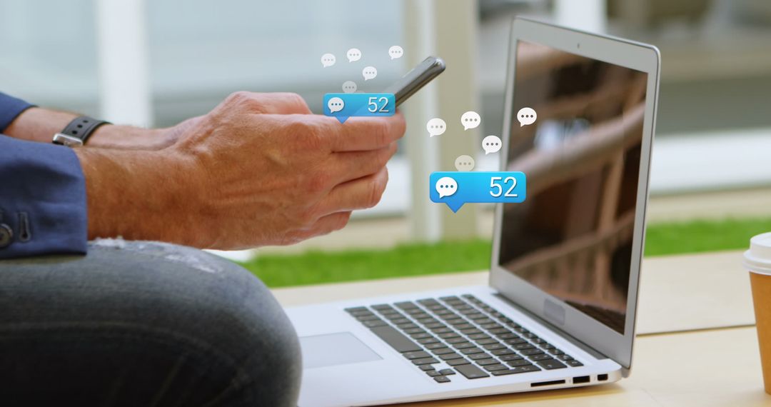 Man Using Smartphone and Laptop with Notifications Displayed