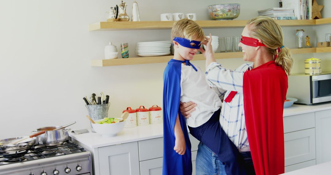 A boy and woman enjoy a playful, bonding moment in superhero attire in the kitchen. - Free Images, Stock Photos and Pictures on Pikwizard.com