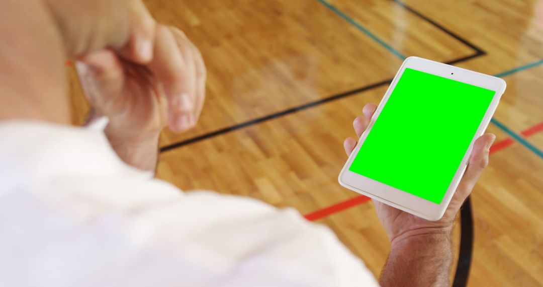 Man Holding Tablet with Green Screen on Basketball Court - Free Images, Stock Photos and Pictures on Pikwizard.com