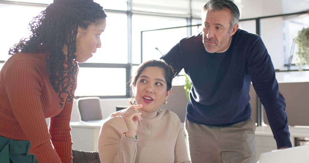 Diverse team collaborating with Asian woman leading discussion in open-plan office