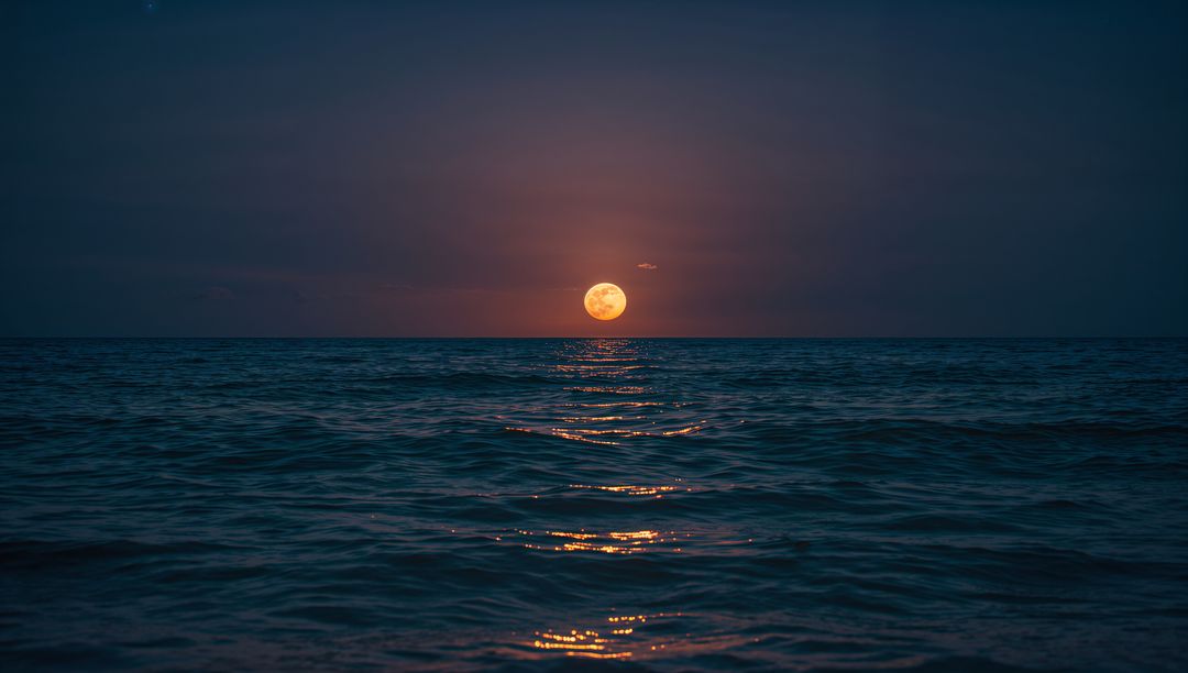 Full Moon Rising Over Calm Ocean Creating Golden Reflection Path to Horizon at Night