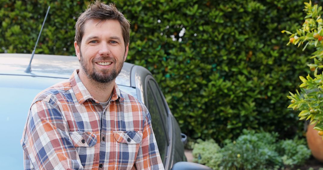 Cheerful Man in Plaid Shirt Leaning on Car Outdoors - Free Images, Stock Photos and Pictures on Pikwizard.com