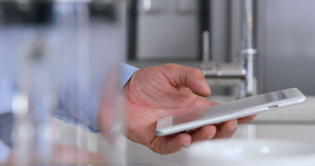 Man Holding Smartphone in Modern Kitchen using Technology - Free Images, Stock Photos and Pictures on Pikwizard.com