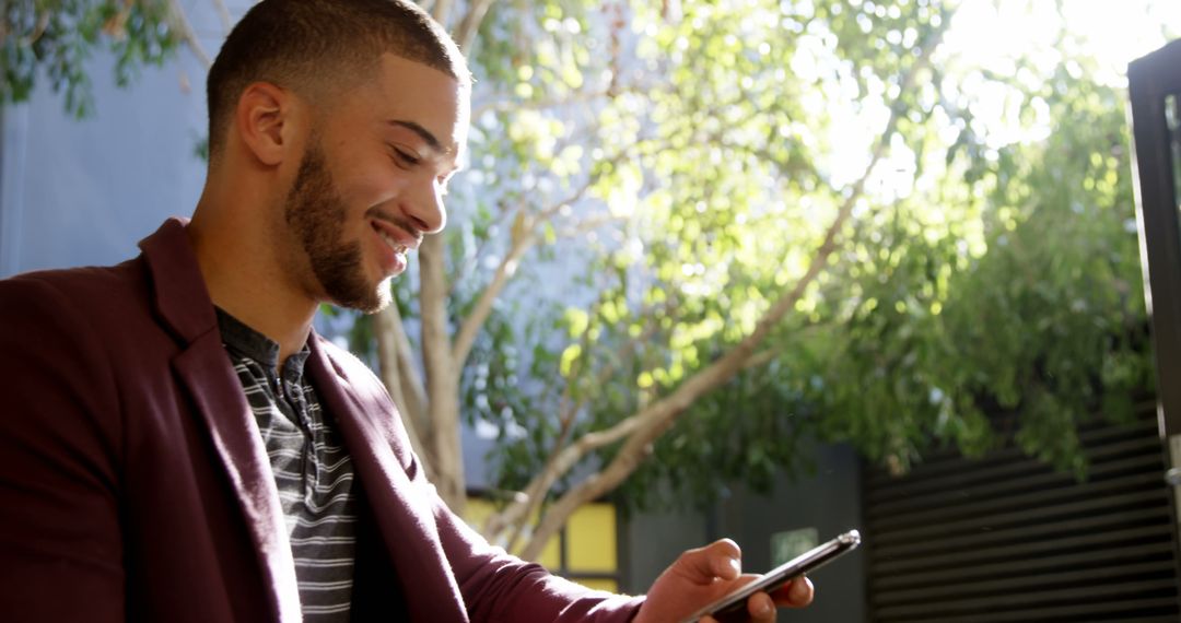 Young Man Smiling Using Smartphone Outdoors - Free Images, Stock Photos and Pictures on Pikwizard.com