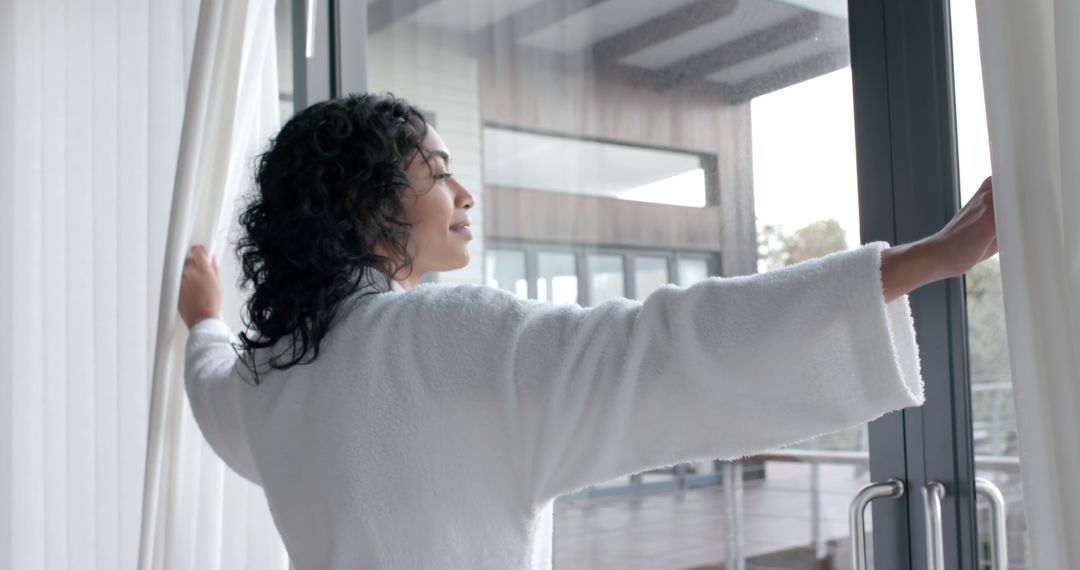 Woman in Bathrobe Opening Curtains in Modern Apartment - Free Images, Stock Photos and Pictures on Pikwizard.com