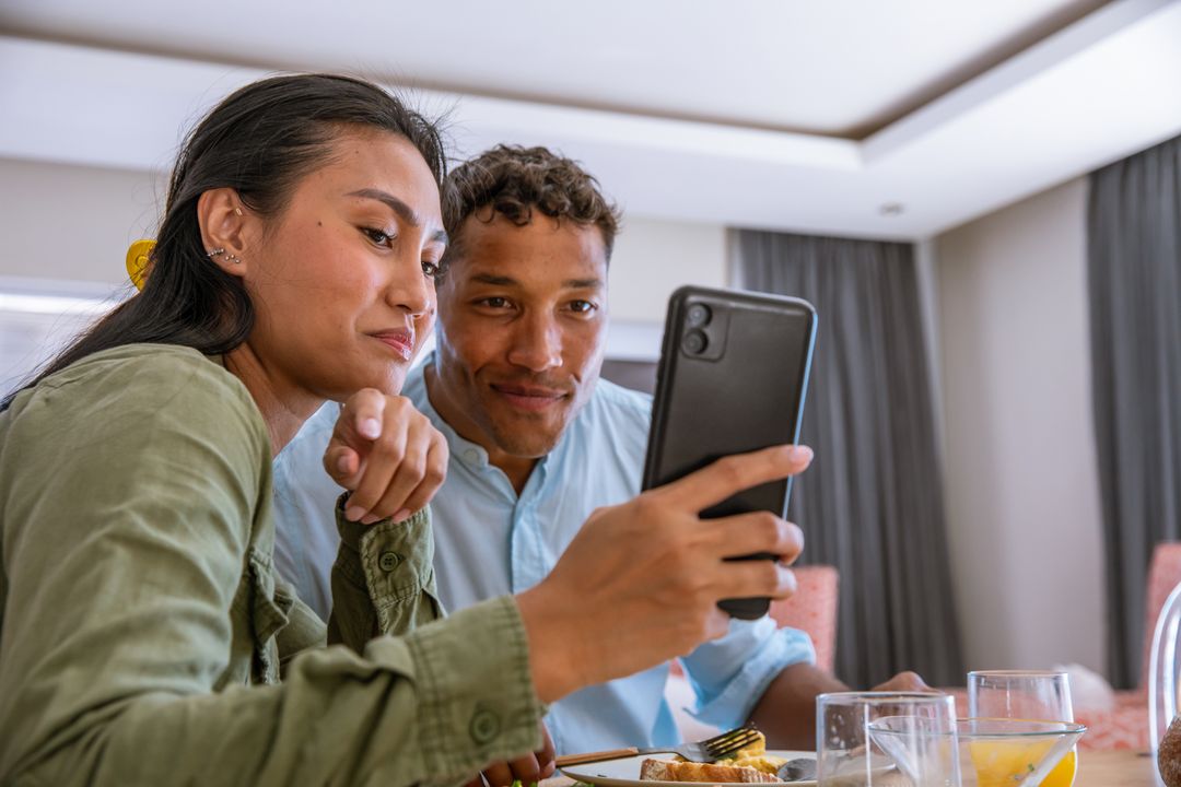 Diverse Couple Enjoying Breakfast Together, Exploring Smartphone Content