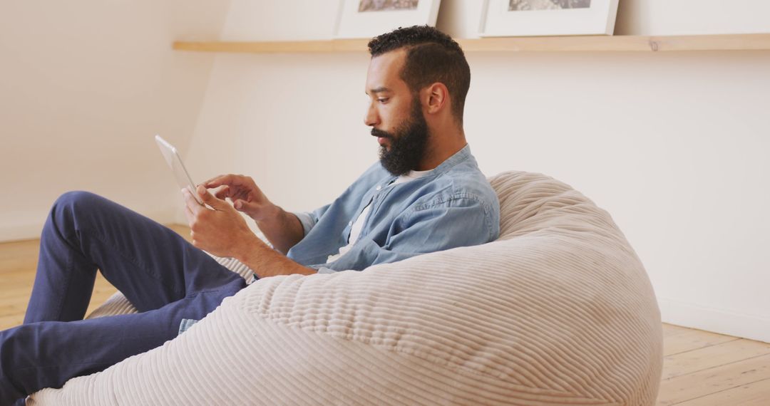 Man Relaxing on Beanbag Using Digital Tablet at Home