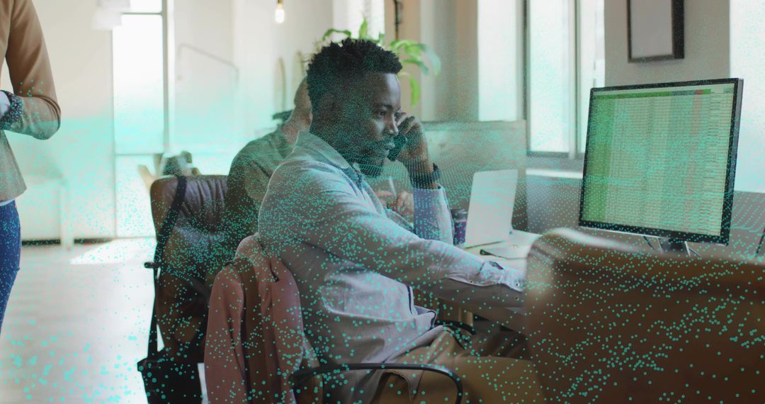 Office worker talking on smartphone while collaborating at desk