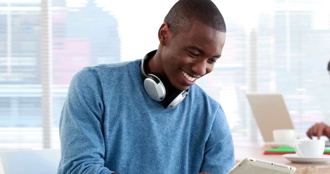 Smiling Man Wearing Headphones Using Digital Tablet in Modern Office - Free Images, Stock Photos and Pictures on Pikwizard.com