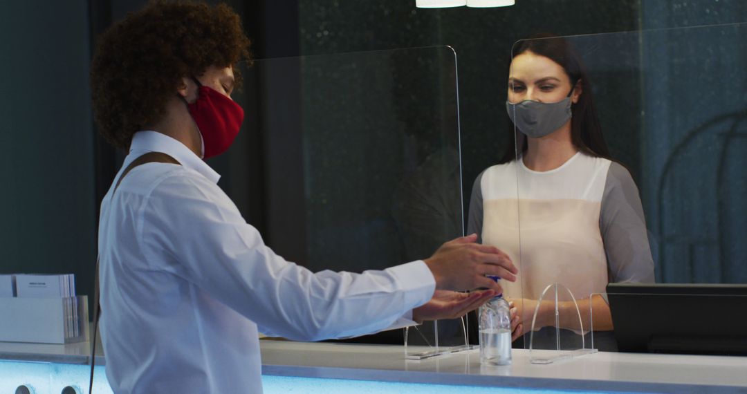 Biracial man and female receptionist wearing face masks at hotel reception desk - Free Images, Stock Photos and Pictures on Pikwizard.com