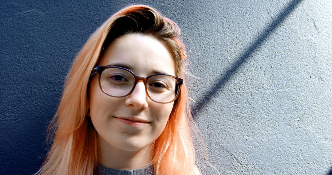 Smiling Woman with Glasses and Pink Hair Against Blue Wall - Free Images, Stock Photos and Pictures on Pikwizard.com