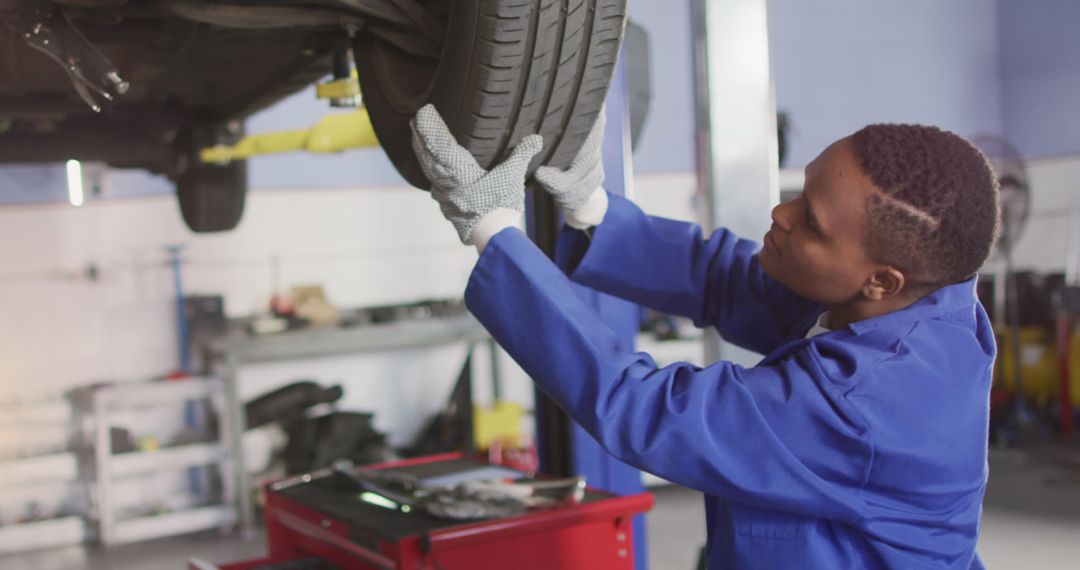 Mechanic Inspecting Car Wheels in Auto Workshop
