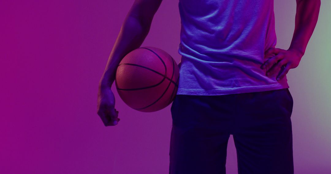 Image of low section of biracial male basketball player with ball on purple to green background - Free Images, Stock Photos and Pictures on Pikwizard.com