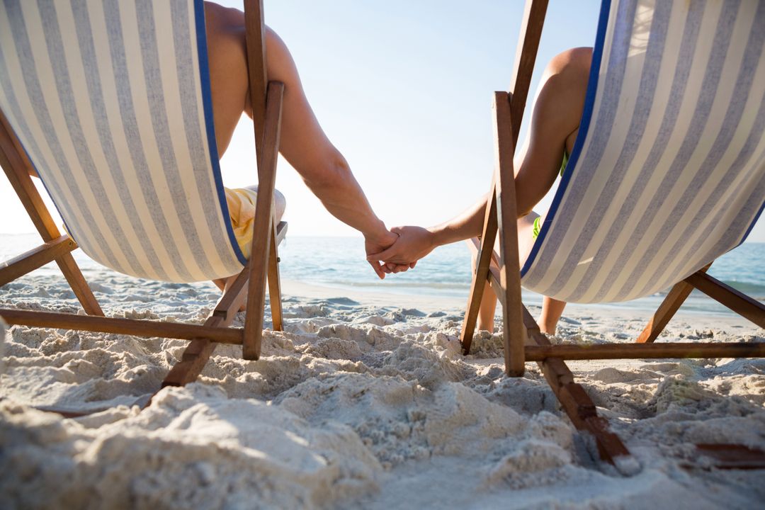 Couple Holding Hands on Beach Loungers - Free Images, Stock Photos and Pictures on Pikwizard.com