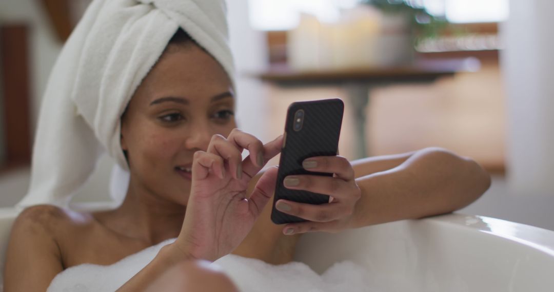 Biracial woman taking a bath and using smartphone - Free Images, Stock Photos and Pictures on Pikwizard.com