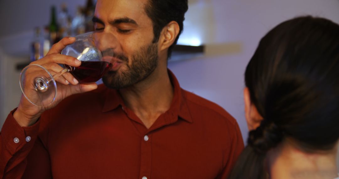 Man enjoying red wine at social gathering indoors - Free Images, Stock Photos and Pictures on Pikwizard.com