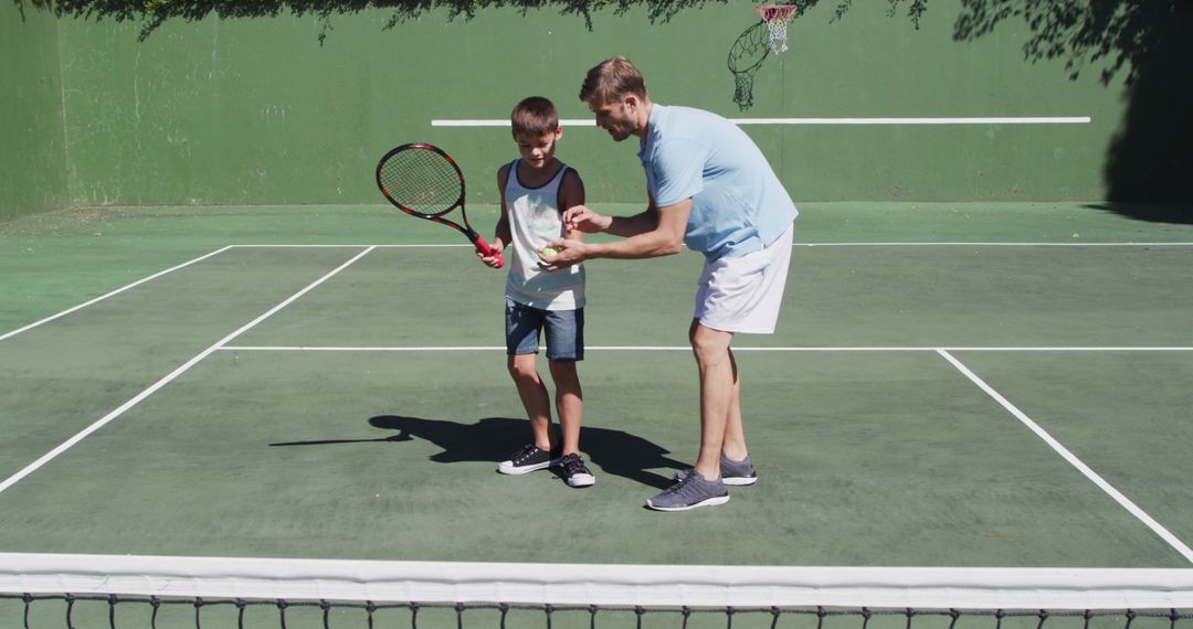 Caucasian father teaching his son to play tennis at tennis court on a bright sunny day - Free Images, Stock Photos and Pictures on Pikwizard.com