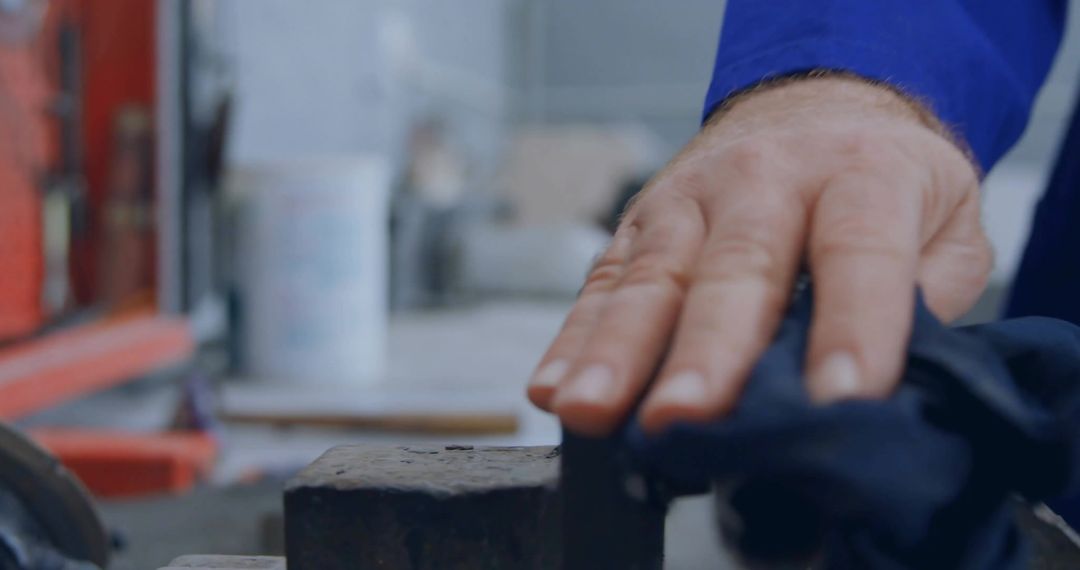 Skilled Hand Wiping Metal Block in Workshop Scene