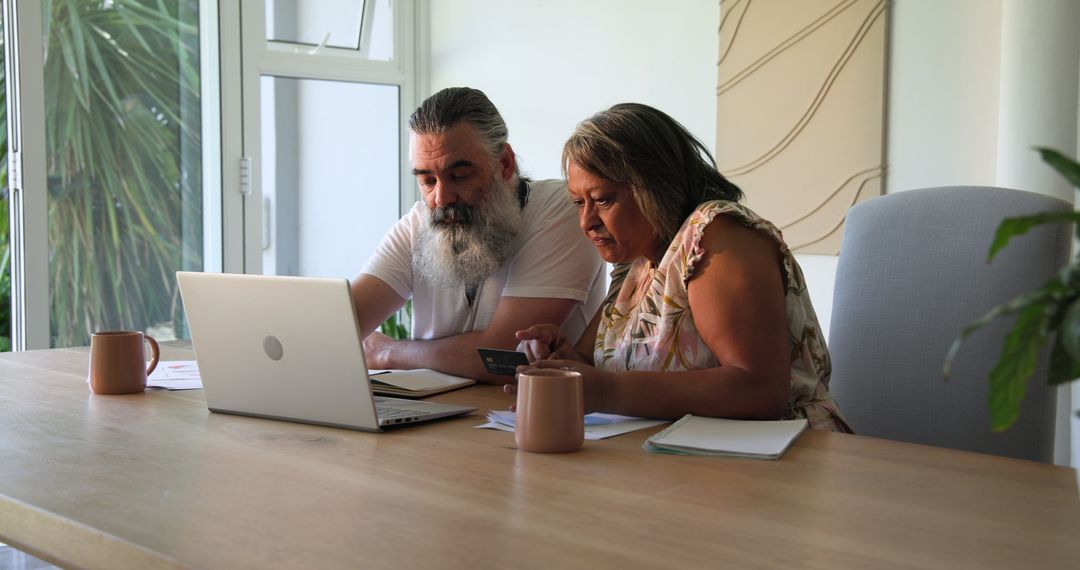 Senior Couple Embracing Technology with Laptop and Smartphone