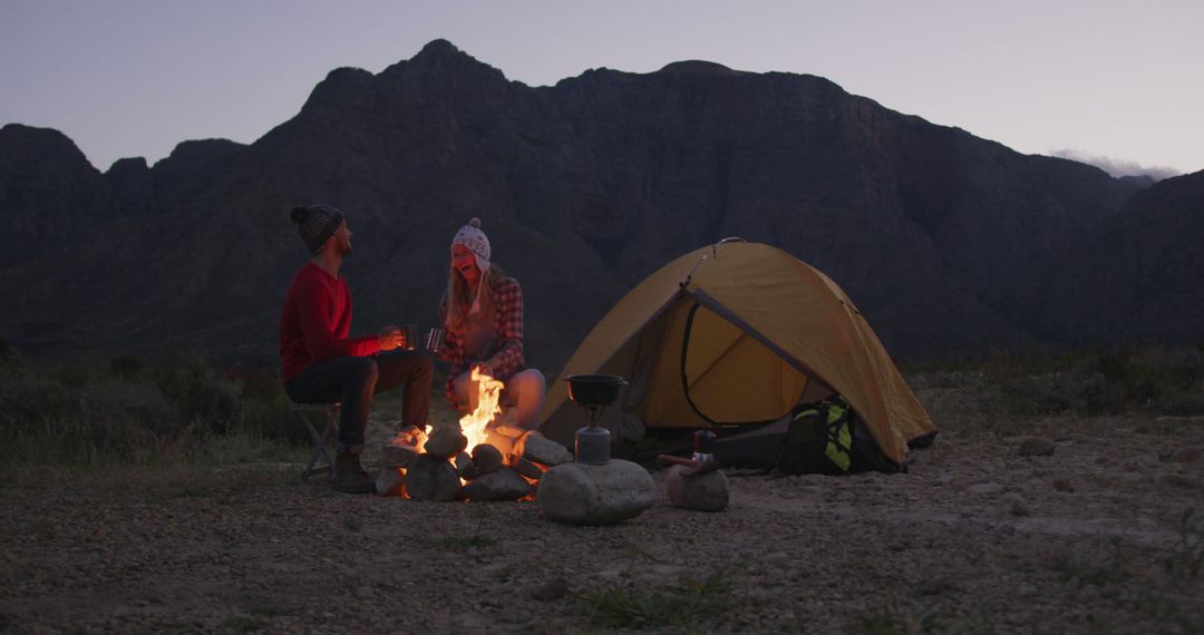 Caucasian couple drinking by fire and tent camping in mountains with copy space - Free Images, Stock Photos and Pictures on Pikwizard.com