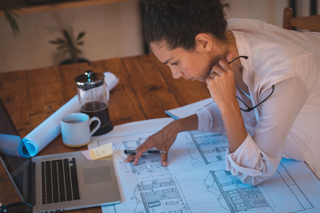 Biracial Woman Studying Architectural Blueprints at Home - Free Images, Stock Photos and Pictures on Pikwizard.com