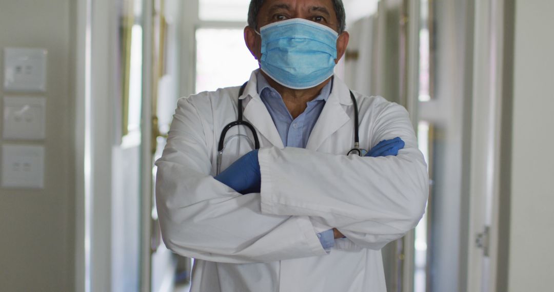 Confident Doctor Wearing Mask and Gloves in Hospital Corridor - Free Images, Stock Photos and Pictures on Pikwizard.com