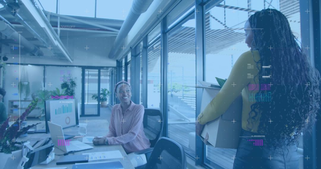 Coworker greeting colleague carrying box in open office, onboarding and teamwork moment