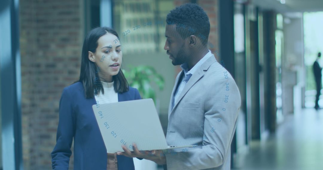 Business Colleagues Analyzing Data on Laptop in Modern Office Corridor