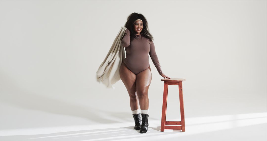 Confident Black Woman Posing in Bodysuit with Red Stool