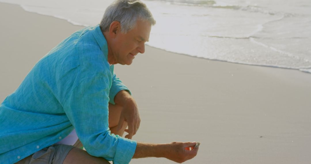 Senior Man Enjoying Sea View Holding Seashell at Beachside